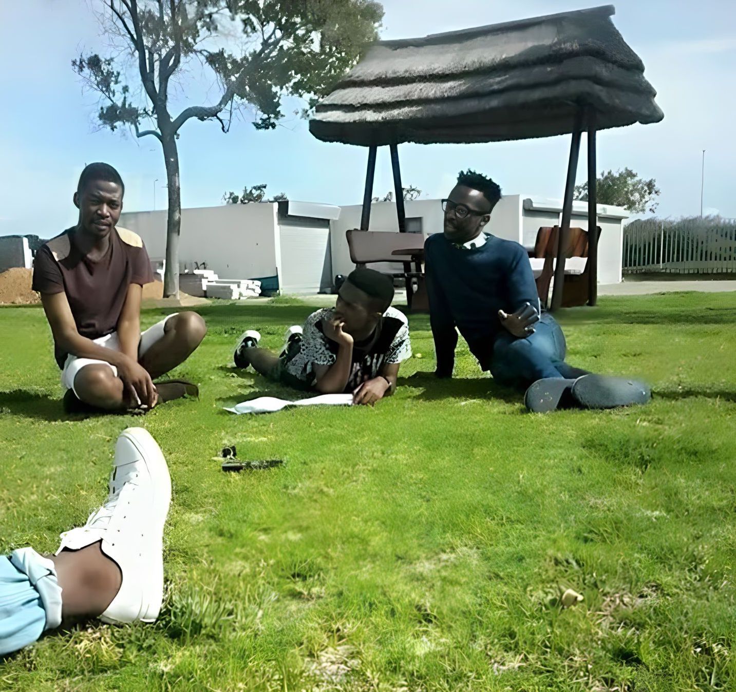Three people sitting on the grass on a sunny day